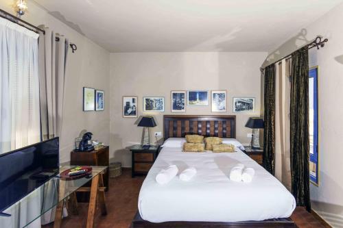 a bedroom with a large white bed and a desk at Hotel Utopía in Benalup Casas Viejas