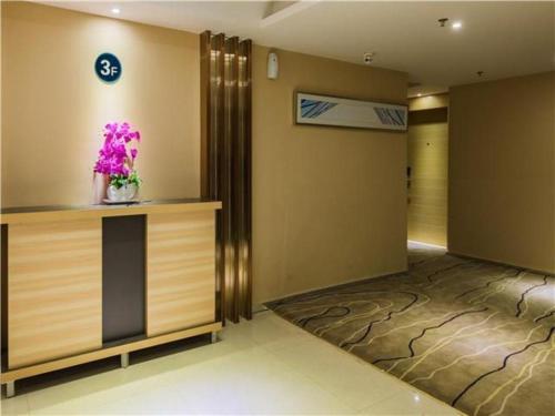 un vestíbulo con un jarrón de flores en un mostrador en City Comfort Inn Hotel Maoming Huazhou Wanda Plaza, en Dongshan