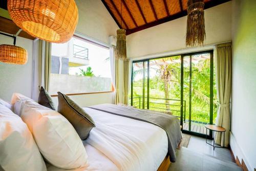 una camera da letto con un letto grande e una grande finestra di Serene 2BR Villa with Lush View 5 mins to Beach a Tanah Lot