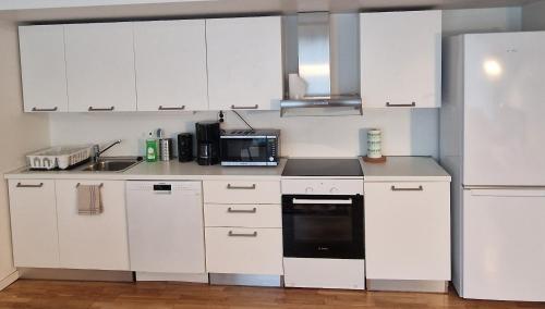 a kitchen with white cabinets and a black appliance at Solace Apartment, Oslo Downtown in Oslo