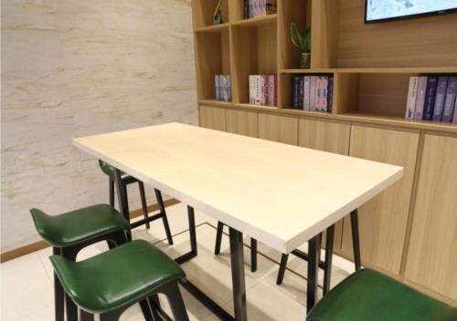 XinningにあるCity Comfort Inn Shaoyang Xinningの図書室の白いテーブルと緑の椅子
