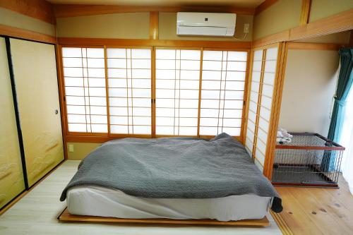 a bedroom with a bed in a room with windows at 宿や晴 in Ioki
