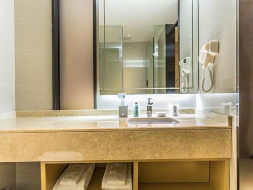 a bathroom with a sink and a mirror at City Comfort Inn Wuzhou High-speed Railway Station Canghai Lake Park in Cangwu
