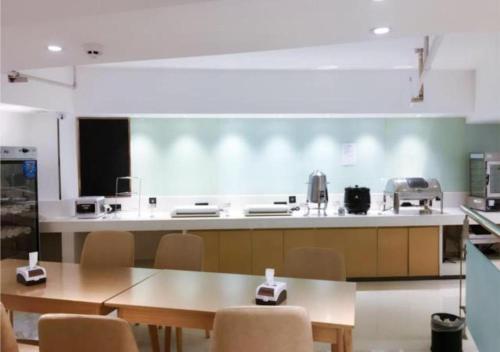 a kitchen with tables and chairs in a room at City Comfort Inn Shaoyang Wugang in Wugang