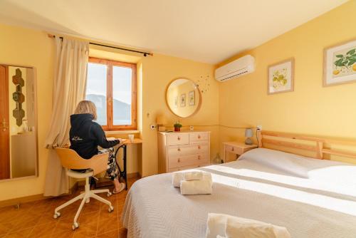 a woman sitting in a chair in a bedroom at Garda Doma in Brenzone sul Garda