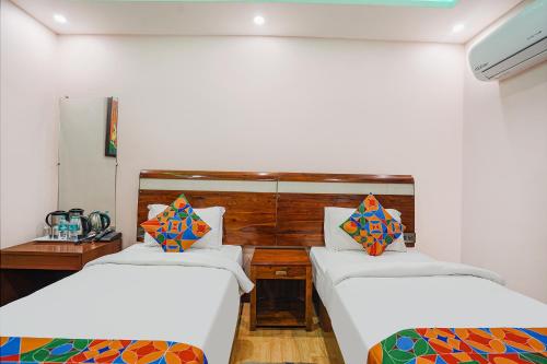 um quarto com duas camas e um espelho em FabHotel Prime Stay inn I em Varanasi