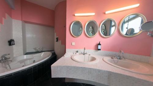 a bathroom with two sinks and a tub and mirrors at Hotel Utopía in Benalup Casas Viejas