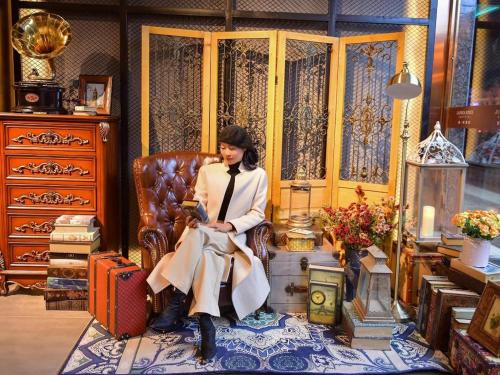 a woman is sitting in a chair with luggage at James Joyce Coffetel Guilin Railway Station Xiangbi Mountain Liangjiang Sihu Wharf in Guilin