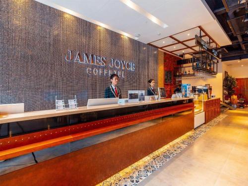 two people standing at a counter in a restaurant at James Joyce Coffetel Kunming Railway Station Huancheng Nan Road Metro Station in Kunming