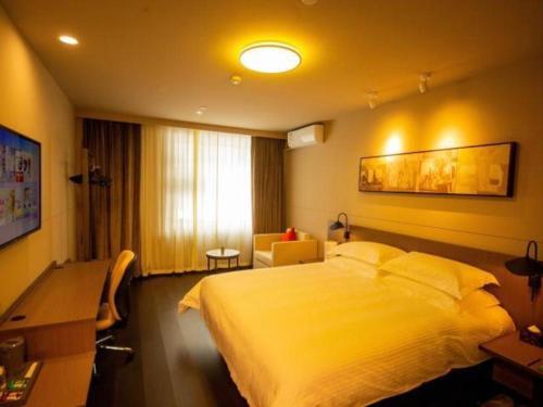 ein Hotelzimmer mit einem großen Bett und einem Schreibtisch in der Unterkunft Jinjiang Inn Select Shihezi East Ring Road in Shihezi