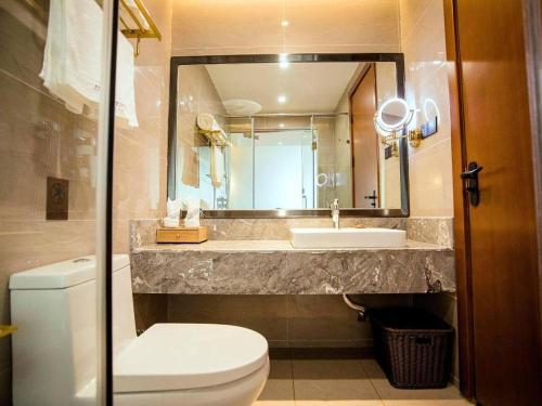 ein Badezimmer mit einem Waschbecken, einem WC und einem Spiegel in der Unterkunft James Joyce Coffetel Xinyang Municipal Government Railway Station in Xinyang