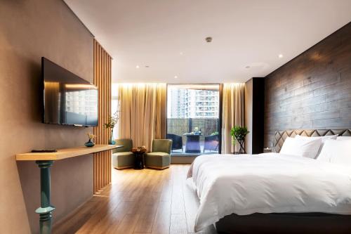 鄭州市にあるM Hotel Zhengzhouのベッド、デスク、窓が備わるホテルルームです。
