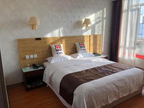 a hotel room with a large bed with two pillows at Pai Hotel Ordos Dongsheng District Yingbin Road in Ordos