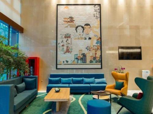 a living room with blue couches and chairs at Magnotel Hotel Guangyuan Nanhe Bus Station Beijing Road in Guangyuan
