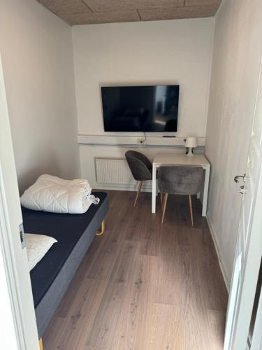 Habitación con cama, escritorio y TV. en Italian Rooms 8, en Aalborg