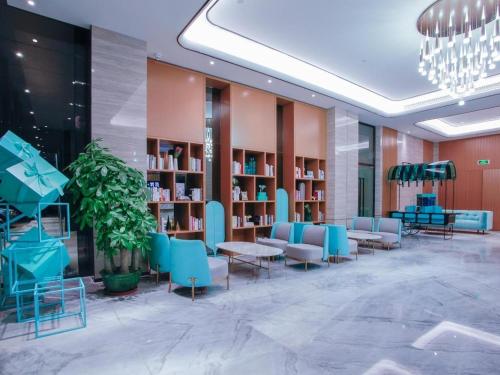 a library with blue chairs and tables and bookshelves at Xana Lite Huizhou Railway Station in Ruhu