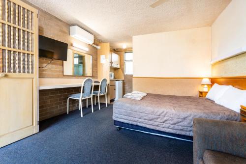 a hotel room with a bed and a kitchen at Town Centre Motor Inn in Merimbula