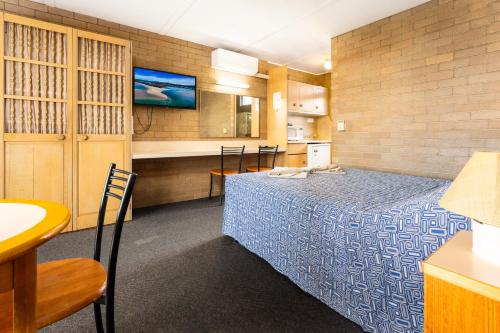 a hotel room with a bed and a kitchen at Town Centre Motor Inn in Merimbula