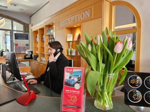 a woman talking on a phone in a store with a vase of flowers at Hotel Am Kaisersaal in Erfurt