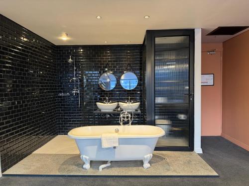 a bath tub in a bathroom with three mirrors at Neighbourgood Loop Street in Cape Town