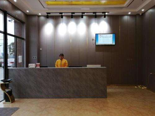 Ein Mann, der hinter einem Tresen in einem Raum steht. in der Unterkunft Shell Hotel Nanyang High-Speed Railway Station Jiangying Airport Huayaocheng in Nanyang