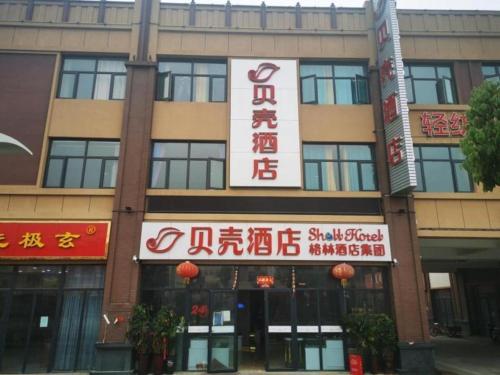 ein Gebäude mit Schildern an der Seite in der Unterkunft Shell Hotel Nanyang High-Speed Railway Station Jiangying Airport Huayaocheng in Nanyang