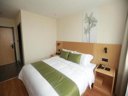 1 dormitorio con 1 cama grande con sábanas blancas y almohadas verdes en GreenTree Inn Express Guangxi Nanning Mingyang Avenue Nanning Airport en Tanbai