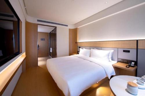 um quarto com uma grande cama branca e uma televisão em JI Hotel Beijing Dazhongsi em Pequim