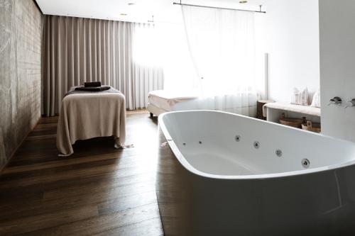 a bath tub in a room with a table at Hotel Weisses Kreuz in Malles Venosta