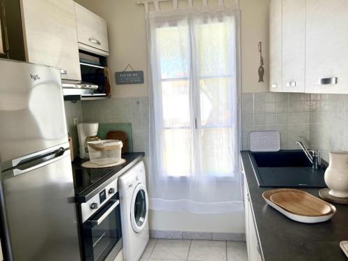 une cuisine avec un réfrigérateur et une machine à laver dans l'établissement AURORE maison confort au Bois Plage, au Bois-Plage-en-Ré