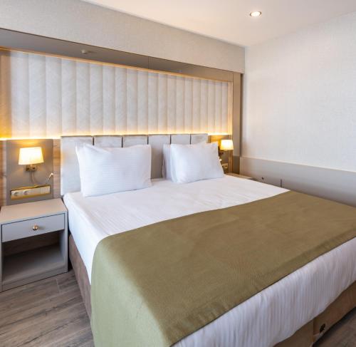 a bedroom with a large white bed with two lamps at Belenli Resort Hotel in Belek