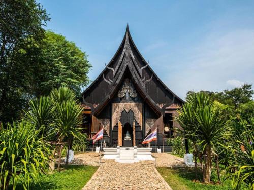 a building with a black roof with flags in front at SC Palace Chiangrai Hotel in Chiang Rai