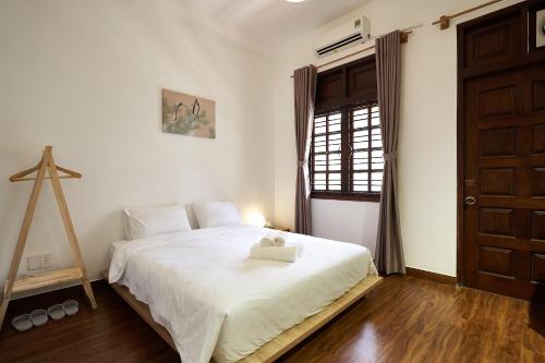 Un dormitorio con una cama blanca con una cruz. en The Hideaway Alley Bui Vien, en Ho Chi Minh