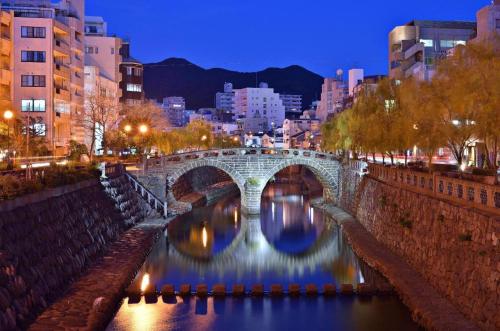 un puente sobre un río en una ciudad por la noche en Coruscant Hotel Nagasaki Station2 en Asahimachi