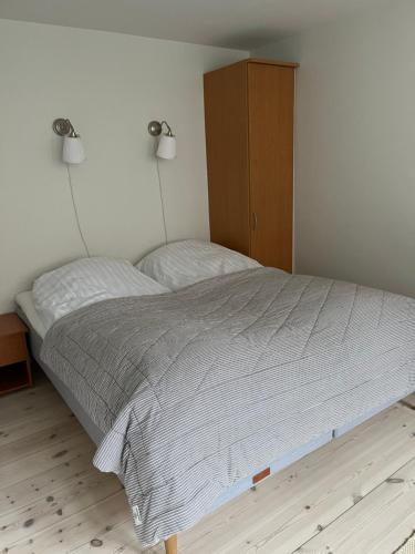 a bedroom with a large bed with a wooden cabinet at Kerteminde-ferielejlighed in Kerteminde