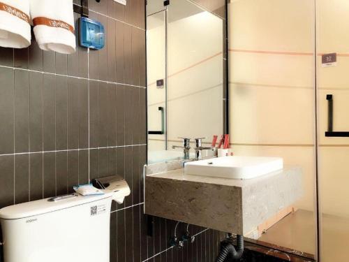ein Bad mit einem Waschbecken und einem Spiegel in der Unterkunft Thank Inn Hotel Inner Mongolia Baotou Donghe Haode Trade Plaza in Baotou