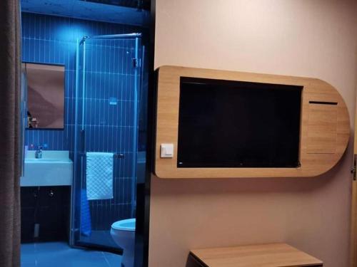 a bathroom with a toilet and a tv on the wall at Thank Inn Hotel Jiangsu Wuxi High-Tech Zone Ruigang Pedestrian Street in Daqiangmen