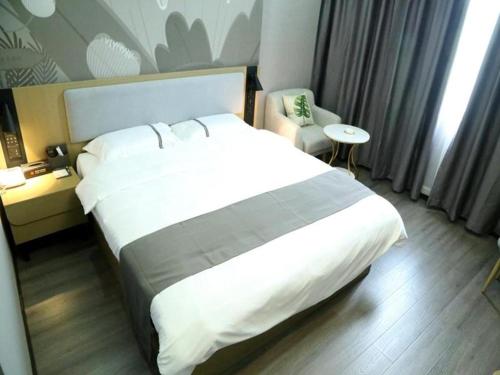 um quarto de hotel com uma cama grande e uma cadeira em Thank Inn Hotel Guangxi Qinzhou Lingshan Renhe 