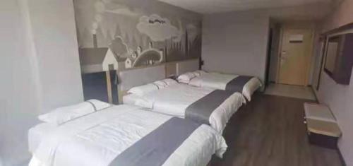 uma fila de três camas num quarto em Thank Inn Hotel Guangxi Qinzhou Lingshan Renhe 