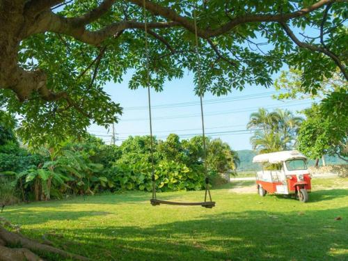 a swing hanging from a tree with a truck in a field at The Beach Terrace Hotel AO Ishigaki in Ishigaki Island