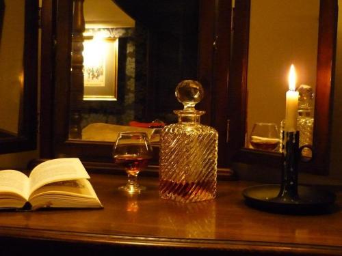 una botella de vino y un libro y una vela sobre una mesa en The Leather Bottle Ltd en Cobham