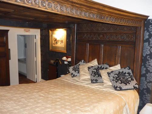 een slaapkamer met een groot bed met kussens erop bij The Leather Bottle Ltd in Cobham