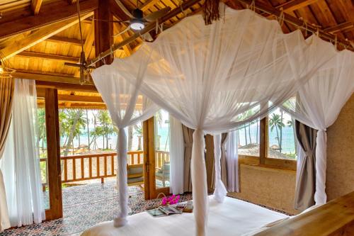a bed with a canopy in a room with windows at Grand Ocean Bay Resort Phu Quoc in Phu Quoc