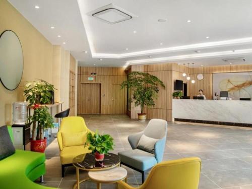 a lobby with yellow and blue chairs and a counter at Green Tree Inn Express Huai'an Huaiyin District Jiangxi Road Normal University in Huai'an