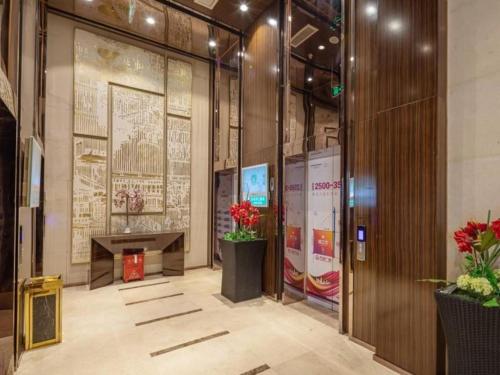 vestíbulo de un edificio con escritorio y flores en VX Hotel Wuxi Xinwu District Executive Center Wanda Plaza en Xin'an