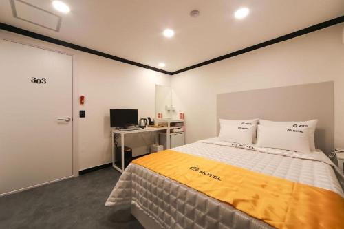 um quarto com uma cama e uma secretária com um computador em Prince Motel em Busan