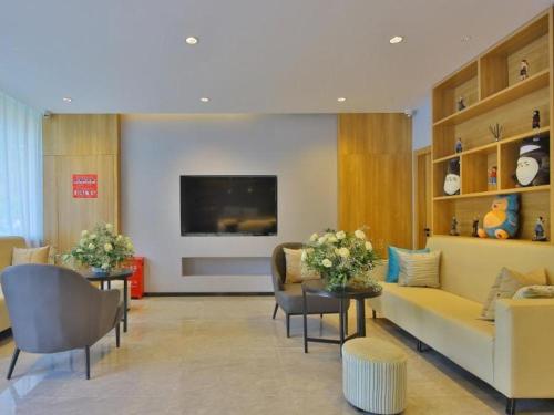 a living room with a couch and chairs and a tv at GreenTree Esports Hotel Qingdao Licang District Wanda in Laoshan