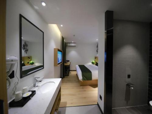 a bathroom with a bed and a sink and a mirror at Green Tree Inn Guangxi Wuzhou 2nd Xinxing Road Liangguang Market in Wuzhou