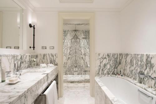 a white bathroom with two sinks and a tub at Rocco Forte Hotel De Russie in Rome