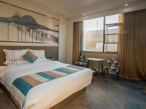 um quarto de hotel com uma cama, uma mesa e uma janela em VX Hotel Shangrao High-Speed Railway Station em Shangrao